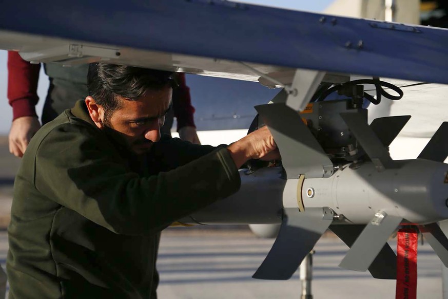 In this picture released by the official website of the Iranian Army, a military technician works on the installation of a smart bomb on a drone during an air force exercise, in Iran, Thursday, Oct. 2 ...