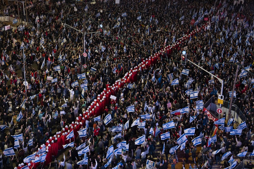 A line of protesters supporting women&#039;s rights, dressed as characters from The Handmaid&#039;s Tale television series, and other Israelis protest against plans by Prime Minister Benjamin Netanyah ...