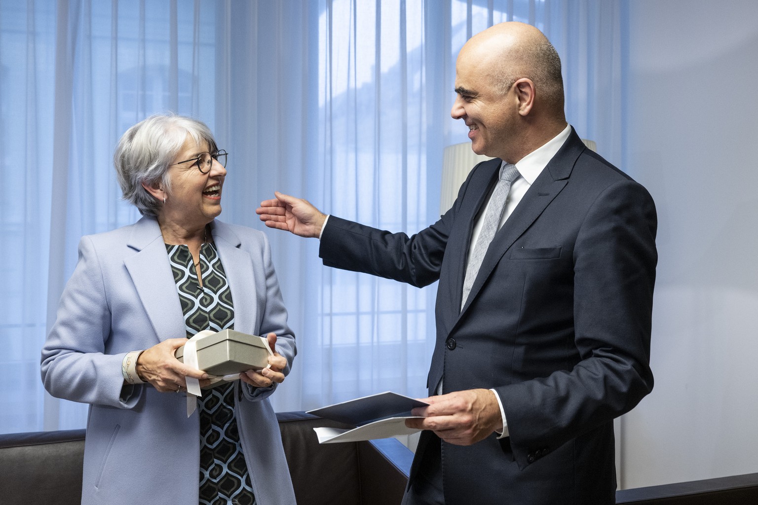 Bundespraesident Alain Berset, rechts, und seine Nachfolgerin Bundesraetin Elisabeth Baume-Schneider tauschen Geschenke aus, am Freitag, 22. Dezember 2023, in Bern. (KEYSTONE/Peter Schneider)