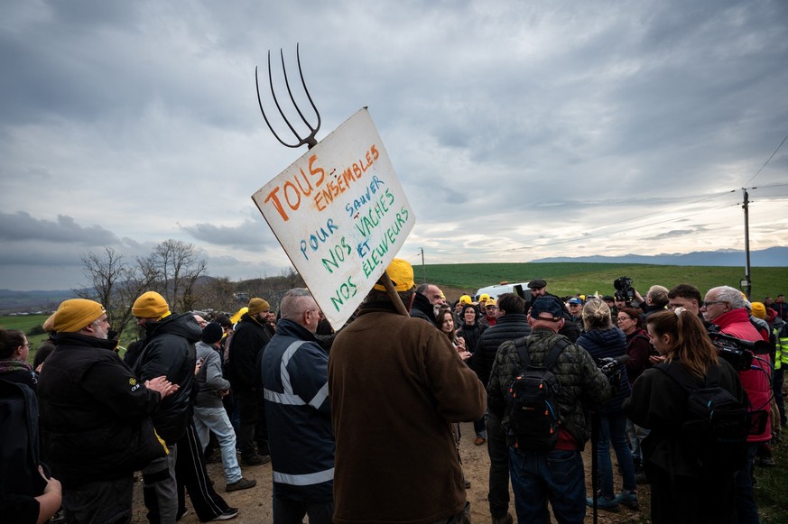 A protester holds a placard reading &quot;All together to save our cows and our farmers&quot; as farmers demonstrate against the slaughter of a 200-cow herd after a case of lumpy skin disease (LSD) wa ...