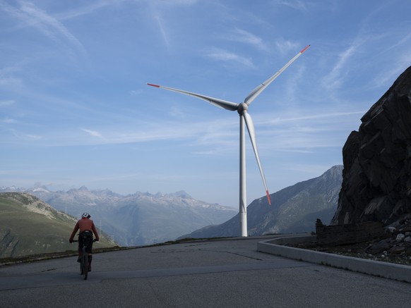 Ein Mountainbiker im Aufstieg zum Cornopass mit Blick auf ein Windrad des Windpark Gries, am Donnerstag, 22. August 2024, im Obergoms. (KEYSTONE/Gian Ehrenzeller)