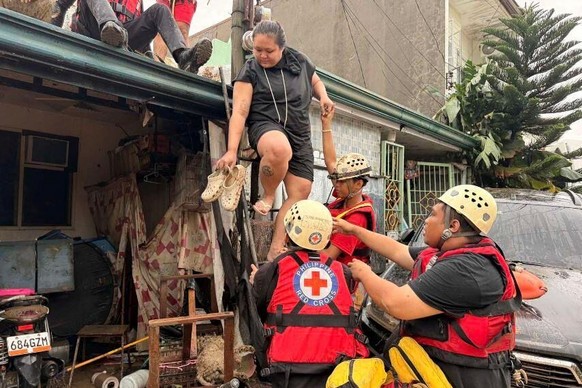 In this photo provided by the Philippine Red Cross, the Water Search and Rescue Team assists individuals trapped on a roof in the Talamban barangay of Cebu, Philippines, Tuesday, Nov. 4, 2025. (Philip ...