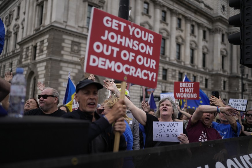 Anti-Brexit protesters sing to music standing on a traffic island across the street from the Houses of Parliament, in London, Wednesday, June 29, 2022. The day before, police officers confiscated soun ...