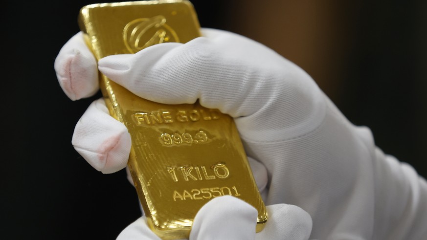 epa12062283 A Bank of Thailand staff member checks the authenticity of a gold bar after receiving the donation, during the handover ceremony at the Bank of Thailand in Bangkok, Thailand, 29 April 2025 ...