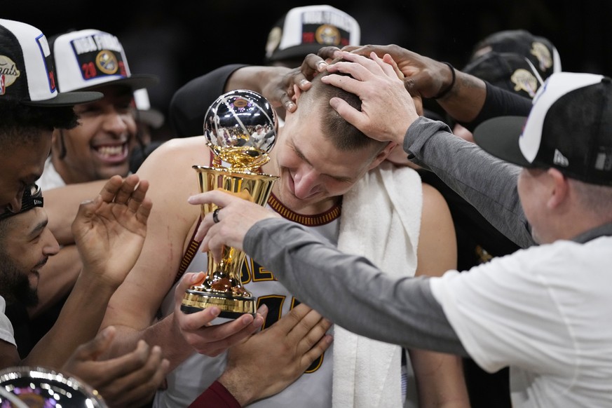 Denver Nuggets center Nikola Jokic is mobbed by teammates after accepting the series MVP trophy in after Game 4 of the NBA basketball Western Conference Final series Monday, May 22, 2023, in Los Angel ...