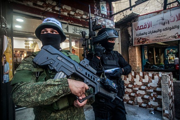 NABLUS, WEST BANK, PALESTINE - 2023/07/15: Palestinian gunmen from the Al-Aqsa Martyrs Brigades appear carrying their weapons during a military parade in the Balata refugee camp, east of Nablus, in th ...
