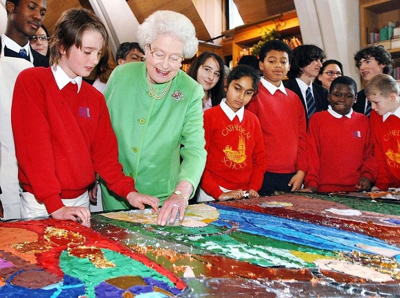 HM Queen Elizabeth II lays a few small mirror tiles around the head of baby Jesus on a nativity collage made by schoolchildren at Southwark Cathedral, December 7, 2006 in London, England. The children ...