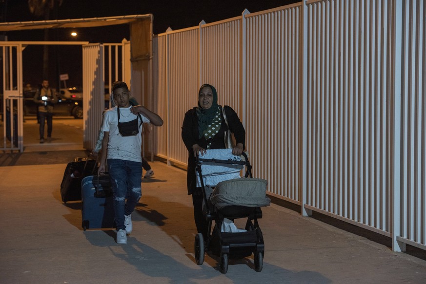 epa09952012 People carry luggage at a border crossing, as seen from Ceuta, Spanish enclave in northern Africa, 17 May 2022. The border between Ceuta and Melilla and northern Africa were opened at midn ...