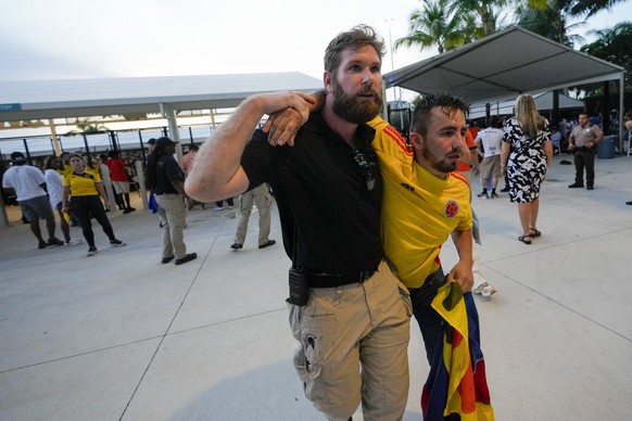 A security agent assists a fan who was waiting to enter the stadium prior to the Copa America final soccer match betwen Argentina and Colombia, in Miami Gardens, Fla., Sunday, July 14, 2024. (AP Photo ...