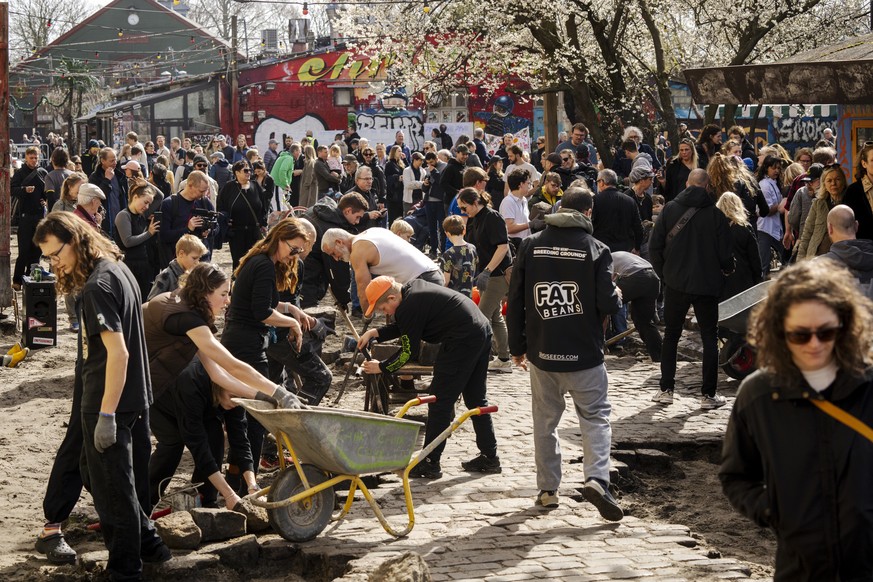 epa11263006 Residents of the free village Christiania jointly dig up the cobblestones at Pusher Street in Copenhagen, Denmark, 06 April 2024. Christiania residents carried out the action in cooperatio ...