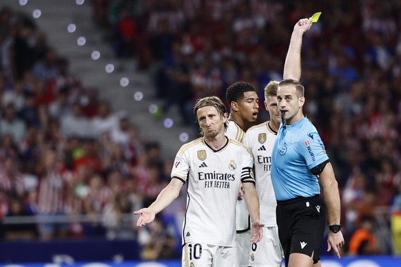 epa10881557 Referee Alberola Rojas (R) shows a yellow card to Real Madrid&#039;s Luka Modric (L) during the Spanish LaLiga soccer match between Atletico Madrid and Real Madrid, in Madrid, Spain, 24 Se ...