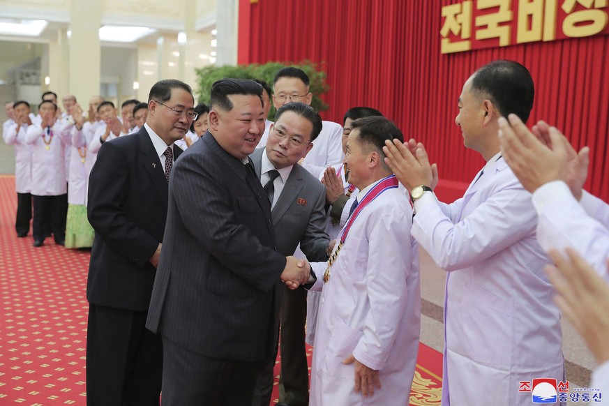 In this photo provided by the North Korean government, North Korean leader Kim Jong Un shakes hands with a health official in Pyongyang, North Korea, Wednesday, Aug. 10, 2022. Kim has declared victory ...