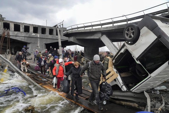 People cross an improvised path under a destroyed bridge while fleeing the town of Irpin close to Kyiv, Ukraine, Monday, March 7, 2022. (AP Photo/Efrem Lukatsky)