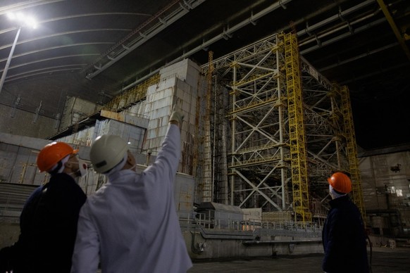 A worker points to the damage of the containment vessel following a drone attack on February 14, 2025, on the New Safe Confinement (NSC) which contains radiation from the remains of reactor 4 of the f ...