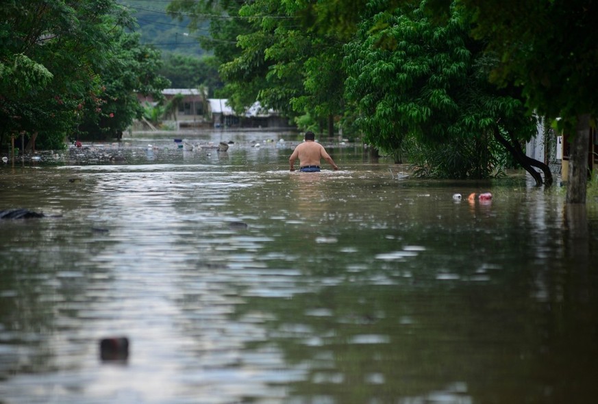A man wades through a flooded street after heavy rains in Poza Rica, Veracruz state, Mexico on October 10, 2025. The heavy rains that occurred on October 9, 2025, in Mexico caused two deaths, as well  ...