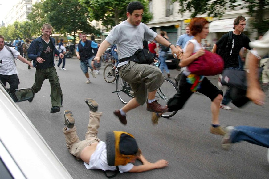 A young man falls, as protesters run away from water cannons and tear gas during clashes with riot police in Geneva, Switzerland, Tuesday, June 3, 2003. After the end of the G8 summit in Evian clashes ...