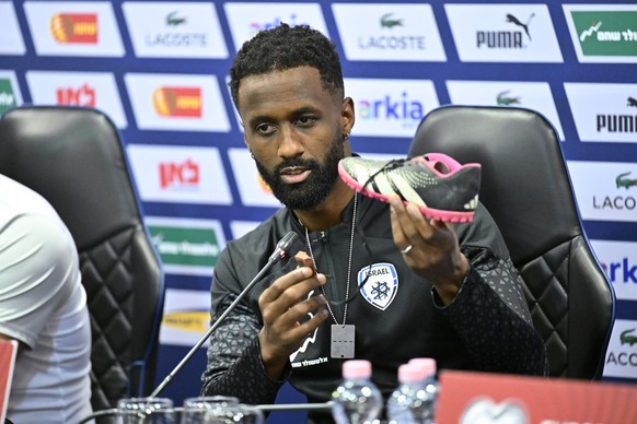 Israel team captain Eli Dasa shows a shoe of a kidnapped Israeli boy during a press conference, before a training session for the Euro 2024 group I qualifying soccer match between Israel and Switzerla ...