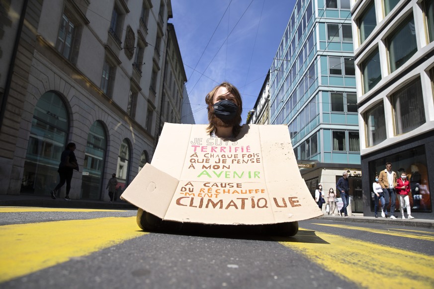 Un militant du collectif d'Extinction Rebellion (XR), avec sa pancarte, fait face à des voitures en pleine rue à Genève.