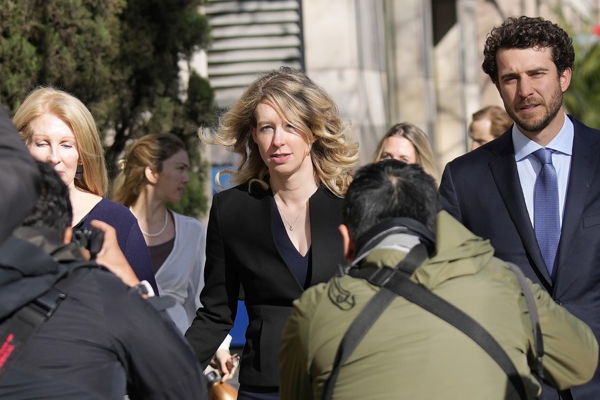 Former Theranos CEO Elizabeth Holmes, middle, walks to federal court with her partner, Billy Evans, right, and her mother, Noel Holmes, in San Jose, Calif., Friday, March 17, 2023. (AP Photo/Jeff Chiu ...