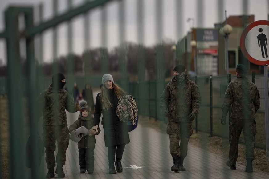 A soldier carries a bag as he is helps a woman and a children fleeing from Ukraine, on their arrival at the border crossing in Medyka, Poland, on Thursday, March 10, 2022. U.N. officials said that the ...