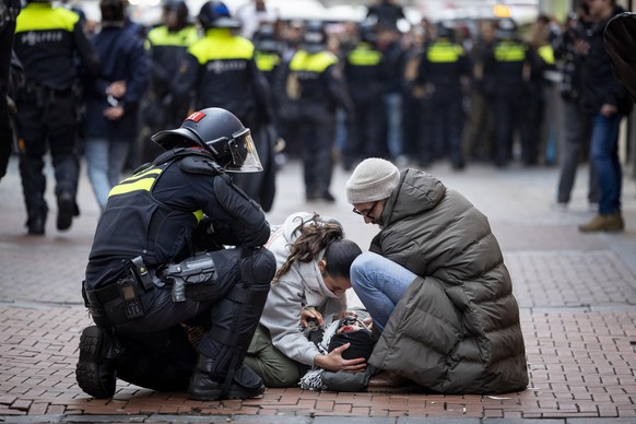 epa11713268 A police officer kneels next to people assisting a bloodied pro-Palestinian protester after a pro-Palestinian protest near Dam Square in Amsterdam, the Netherlands, 10 November 2024. The p ...
