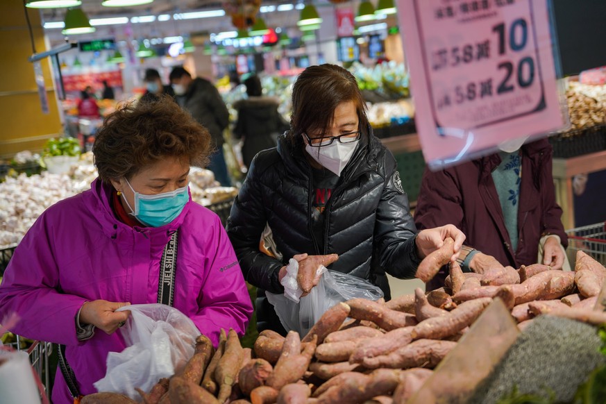 Des personnes achetant des légumes sur un marché de Pékin, en Chine.