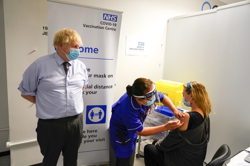 FILE - In this June 21, 2021, file photo, Britain&#039;s Prime Minister Boris Johnson, left watches as a woman receive her COVID-19 vaccine, as he visits a vaccination center at the StoneX Stadium, ho ...