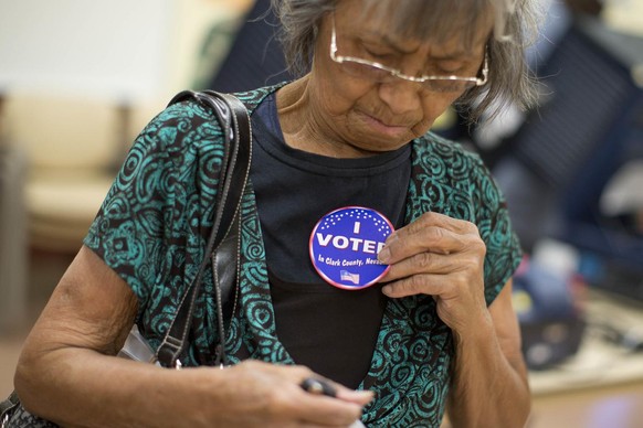 Aida Castillo places a sticker on her blouse indicating that she had voted during the early voting period, Saturday, Oct. 20, 2012, in Las Vegas. In the heavily-Hispanic neighborhoods of Las Vegas, un ...