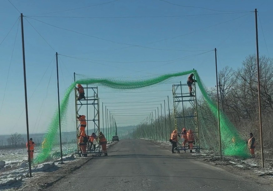 Des ouvriers construisent un tunnel en filet contre les attaques de drones.