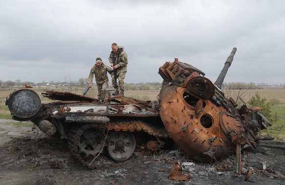 epaselect epa09893158 Ukrainian servicemen inspect a destroyed Russian tank in Rusaniv, outskirts of Kyiv, Ukraine, 16 April 2022. Russian troops entered Ukraine on 24 February resulting in fighting a ...