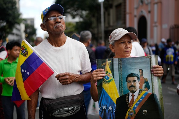 A supporter holds a poster of Venezuelan President Nicolás Maduro in Caracas, Venezuela, Saturday, Jan. 3, 2026, after U.S. President Donald Trump announced that Maduro had been captured and flown out ...