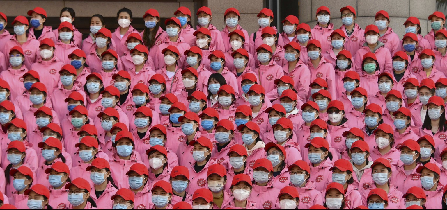 In this photo released by Xinhua News Agency, medical workers gather near a banner which reads &quot;Unite as one, resolutely win the battle against epidemic prevention and control&quot; during a depa ...