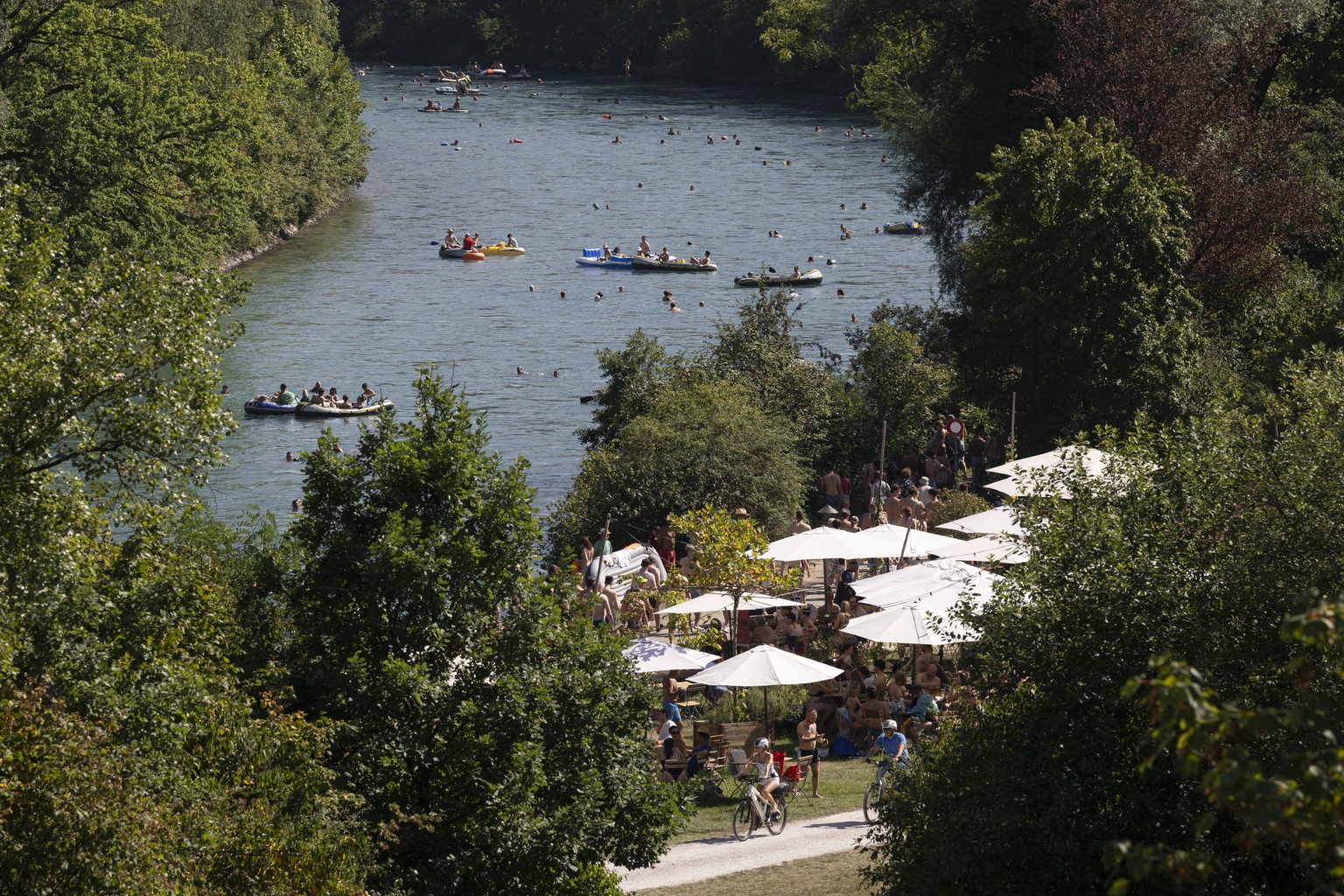 epa10810777 People swim and sail on inflatable boats, on the Aare River, next to Marzili, during the sunny and warm weather in Bern, Switzerland, 20 August 2023. Many parts of Switzerland have been ex ...