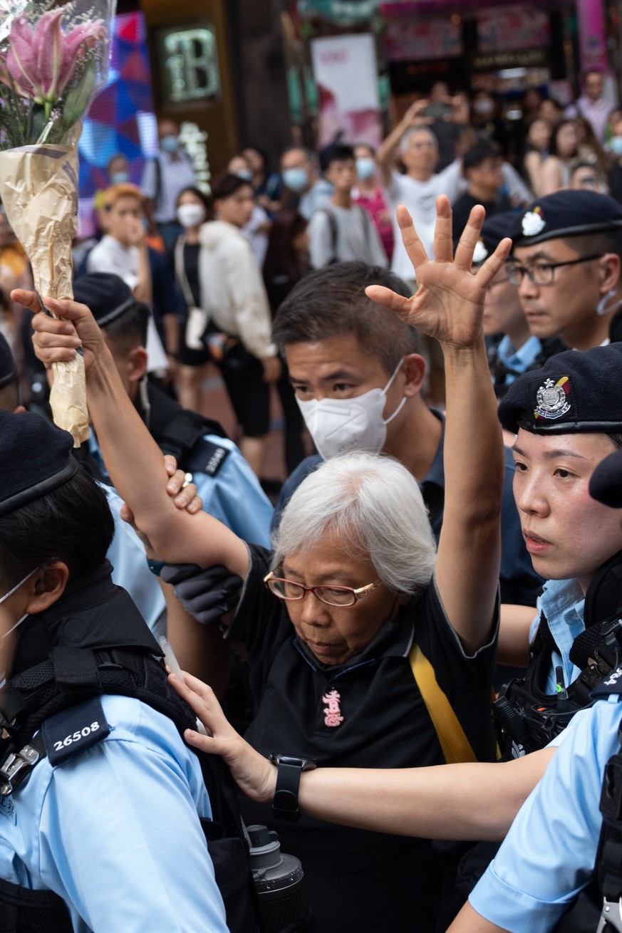 epa10672586 Police escorts a woman known as Grandma Wong to the police car in a shopping area near Victoria Park in Hong Kong, China, 04 June 2023. The annual candlelight vigil in Victoria Park is can ...