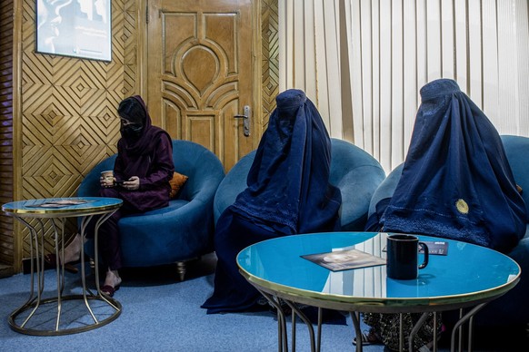 In this photograph taken on August 31, 2025, Afghan burqa-clad women, having appointments for laser treatments, sit in a waiting room at a beauty clinic in Kabul. Decked with fake crystal chandeliers  ...