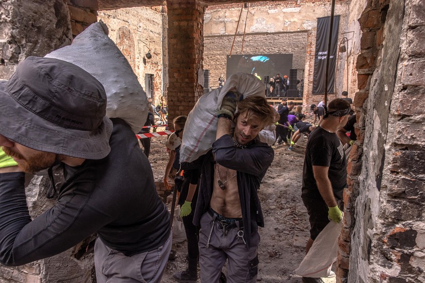 epa10157248 Volunteers from the &#039;Repair Together&#039; group attending the rave event carry bags with debris as they clean up the local House of Culture that was destroyed during the Russian inva ...