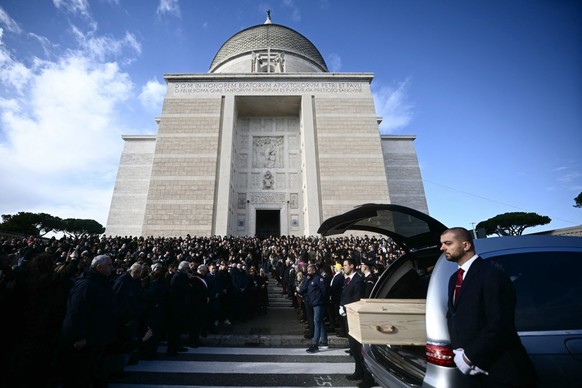 People gather outside the church of Saints Peter and Paul at the end of the funeral of Riccardo Minghetti, one of the Italian victims fo the Crans-Montana new-year fire, in the EUR district of Rome, o ...