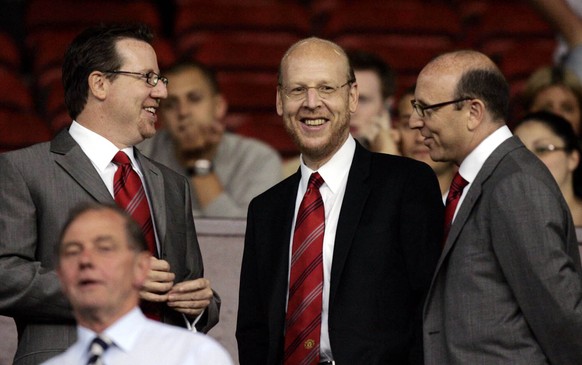 FILE- Manchester United board members Bryan Glazer, left, Avi Glazer, center, and Joel Glazer take their seats in the stands before their side&#039;s Champions League third qualifying round first leg  ...