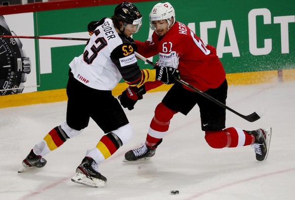 epa09245373 Fabrice Herzog (R) of Switzerland in action against Moritz Seider (L) of Germany during the IIHF Ice Hockey World Championship 2021 quarter final match between Switzerland and Germany at t ...