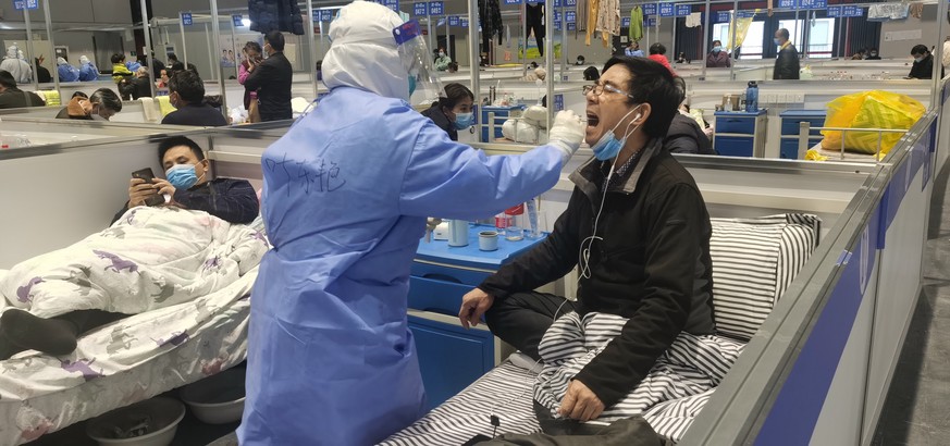 epa09895759 Nurses take swab samples of people for nucleic acid test in a temporary hospital for Covid-positive people in Shanghai, China, 18 April 2022. On 18 April 2022, there were 3 deaths reported ...