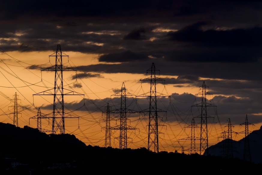 Le soleil se couche derriere les pylones de la ligne a haute tension du reseau electrique le samedi 28 mai 2022 a Collonges en Valais. (KEYSTONE/Jean-Christophe Bott)