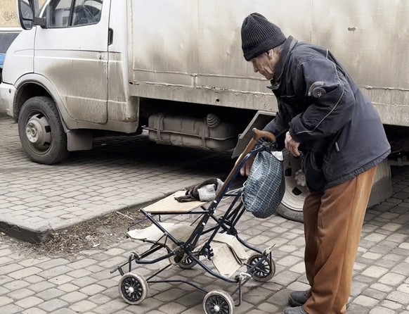 Un vieil homme avec une poussette transformée en véhicule de transport sur le marché de Kostiantiniwka.