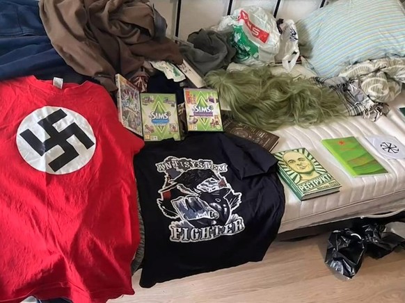 Un t-shirt avec une croix gammée, entre autres, est censé souligner les convictions nazies du suspect. Au centre de l'image : trois pochettes du jeu vidéo <em>Sims</em>.