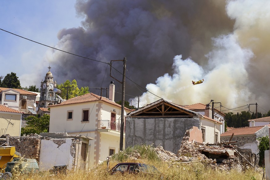 A firefighter aircraft drops water over a forest fire as smoke rises near Vrisa village, on the eastern Aegean island of Lesbos, on Sunday, July 24, 2022. A fire that broke Saturday morning on the Gre ...