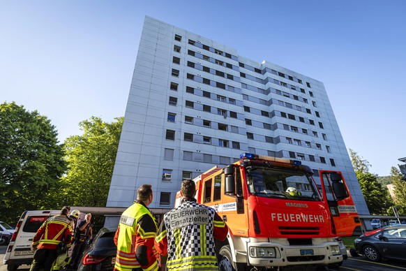Einsatzkraefte der Feuerwehr bei einem Gebaeude nach einem Brand in einem Mehrfamilienhaus in Spreitenbach, am Montag, 8. Juli 2024. Gemaess Polizeiangaben wurden beim Brand, der im Eingangsbereich ei ...