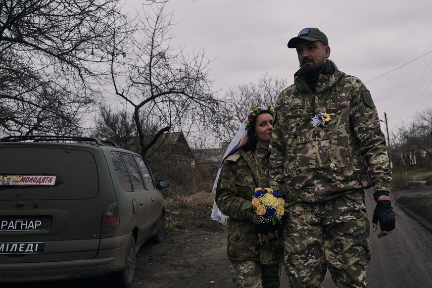 Ukrainian army medics Eugenia and Oleksander, right, arrive to their wedding ceremony in Lyman, Donetsk region, Ukraine, Saturday, Dec. 24, 2022. (AP Photo/Felipe Dana)