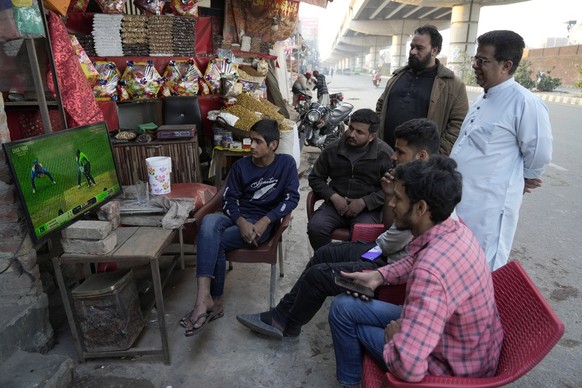 Cricket fans watch the ICC Champions Trophy cricket match between Pakistan and India on a television at a roadside shop in Lahore, Pakistan, Sunday, Feb. 23, 2025. (AP Photo/K.M. Chaudary)