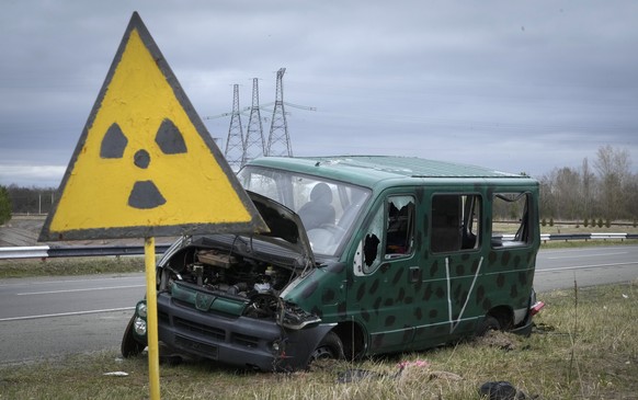 FILE - A radiation sign is seen near a broken Russian vehicle with a V letter, a sign of the Russian army, close to the Chernobyl nuclear power plant in Chernobyl, Ukraine, April 16, 2022. (AP Photo/E ...