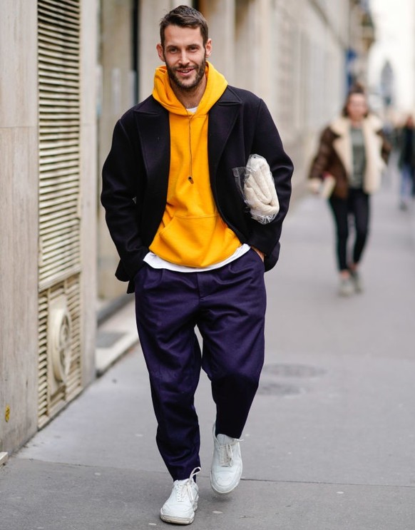 PARIS, FRANCE - MARCH 05: Simon Porte Jacquemus wears a yellow hoodie sweater, a black jacket, large pants, white sneakers shoes, outside APC, during Paris Fashion Week Womenswear Fall/Winter 2018/201 ...