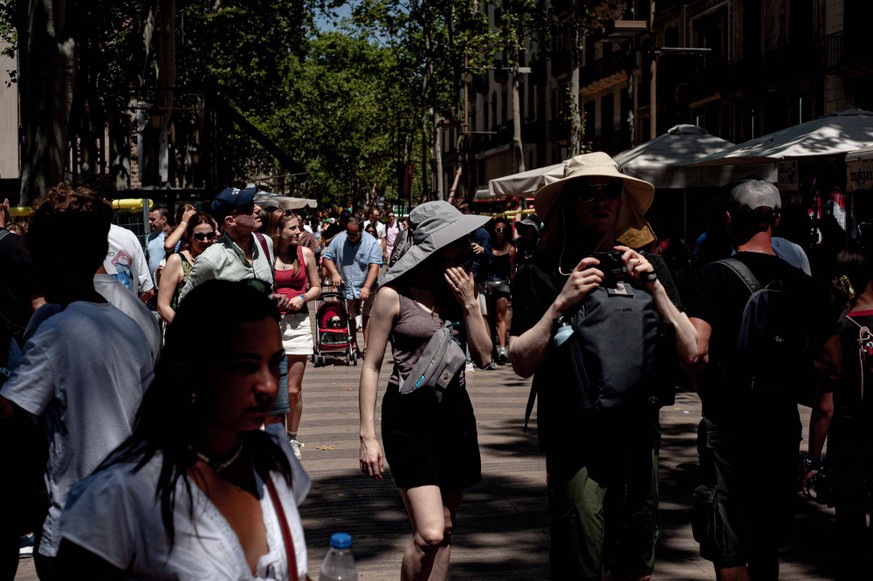 July 14, 2025, Barcelona, Spain: Tourists wear hats to protect themselves from the sun and the high temperatures as they walk along Barcelona s la Rambla, one of the most visited hotspots in the Catal ...